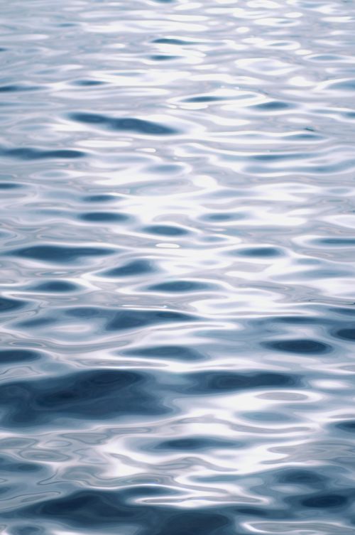 Free Calm ocean surface with gentle waves reflecting sunlight in a tranquil scene. Stock Photo