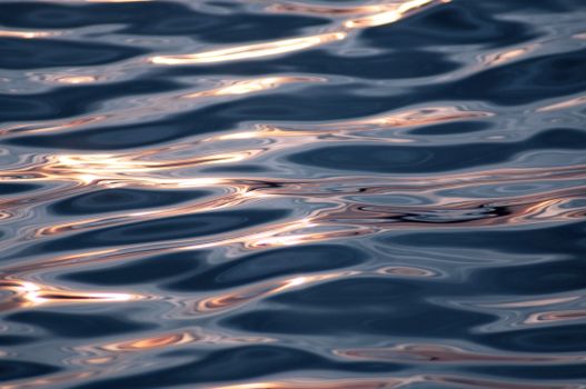 Close-up of shimmering water ripples reflecting sunlight at sunset, creating a calming visual texture.