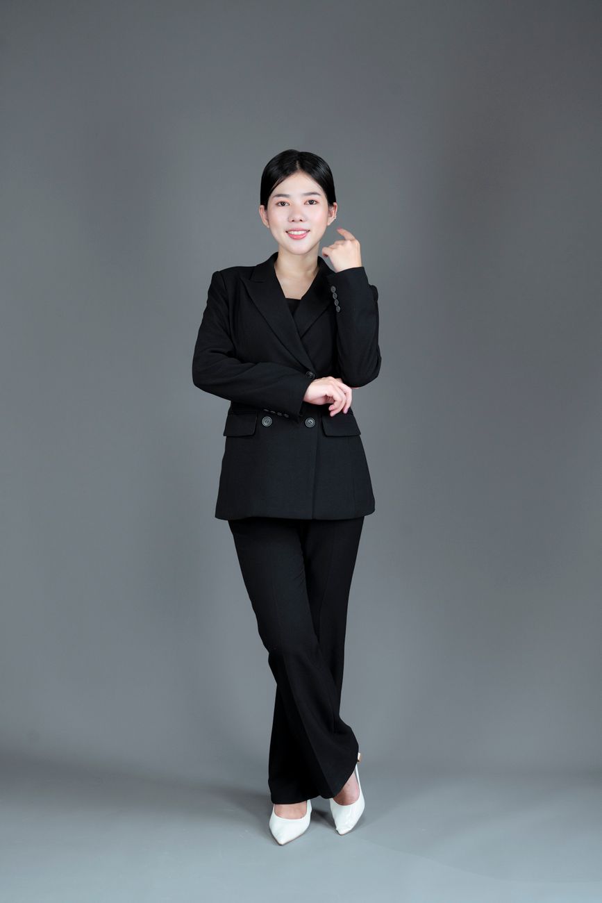 Portrait of an Asian businesswoman confidently posing in a studio wearing a black suit against a gre