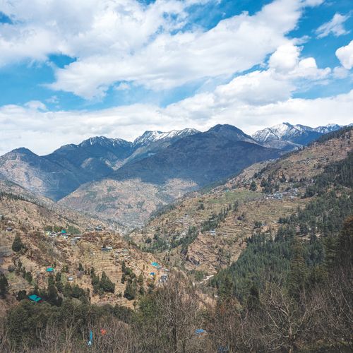 Free Breathtaking view of snow-topped mountains and lush valleys under a cloudy blue sky. Stock Photo
