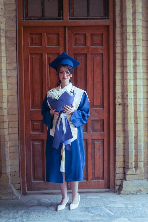 Free Elegant woman in graduation attire posing by a traditional door in Baghdad. Stock Photo