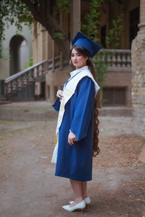 Free Young woman in blue graduation attire standing outdoors with elegant demeanor. Stock Photo