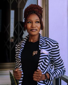 Portrait of a black woman in a striped blazer, exuding confidence and style. Ideal for fashion and lifestyle content.