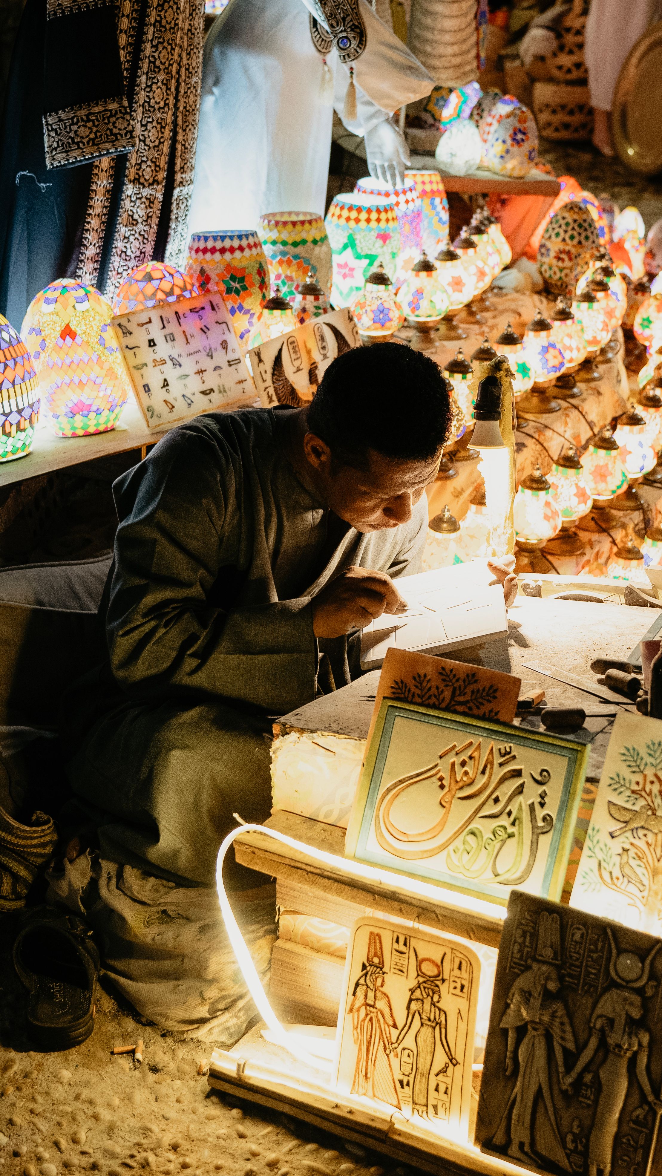 An artisan creating handmade crafts in a vibrant Egyptian night market in Sharm El Sheikh.