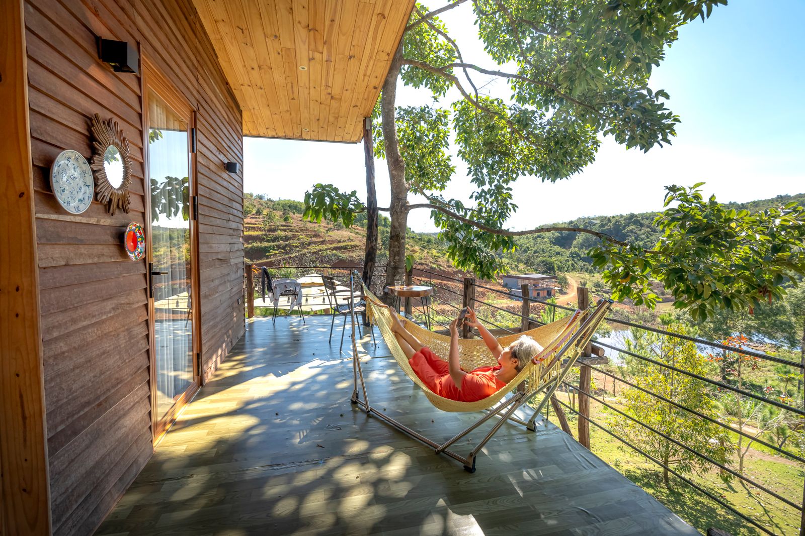 A traveler resting in a hammock on a wooden terrace above a valley. Photo by Quang Nguyen Vinh on Pexels