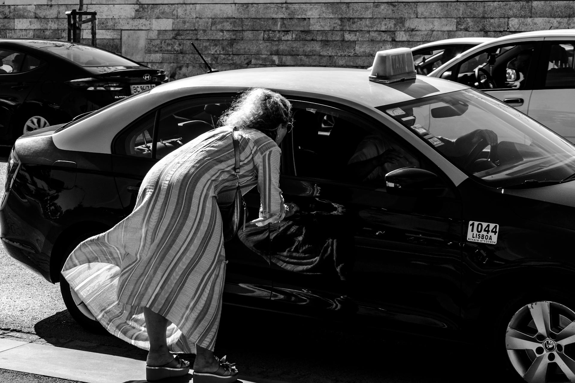 A woman interacting with a taxi driver on a busy Lisbon street.