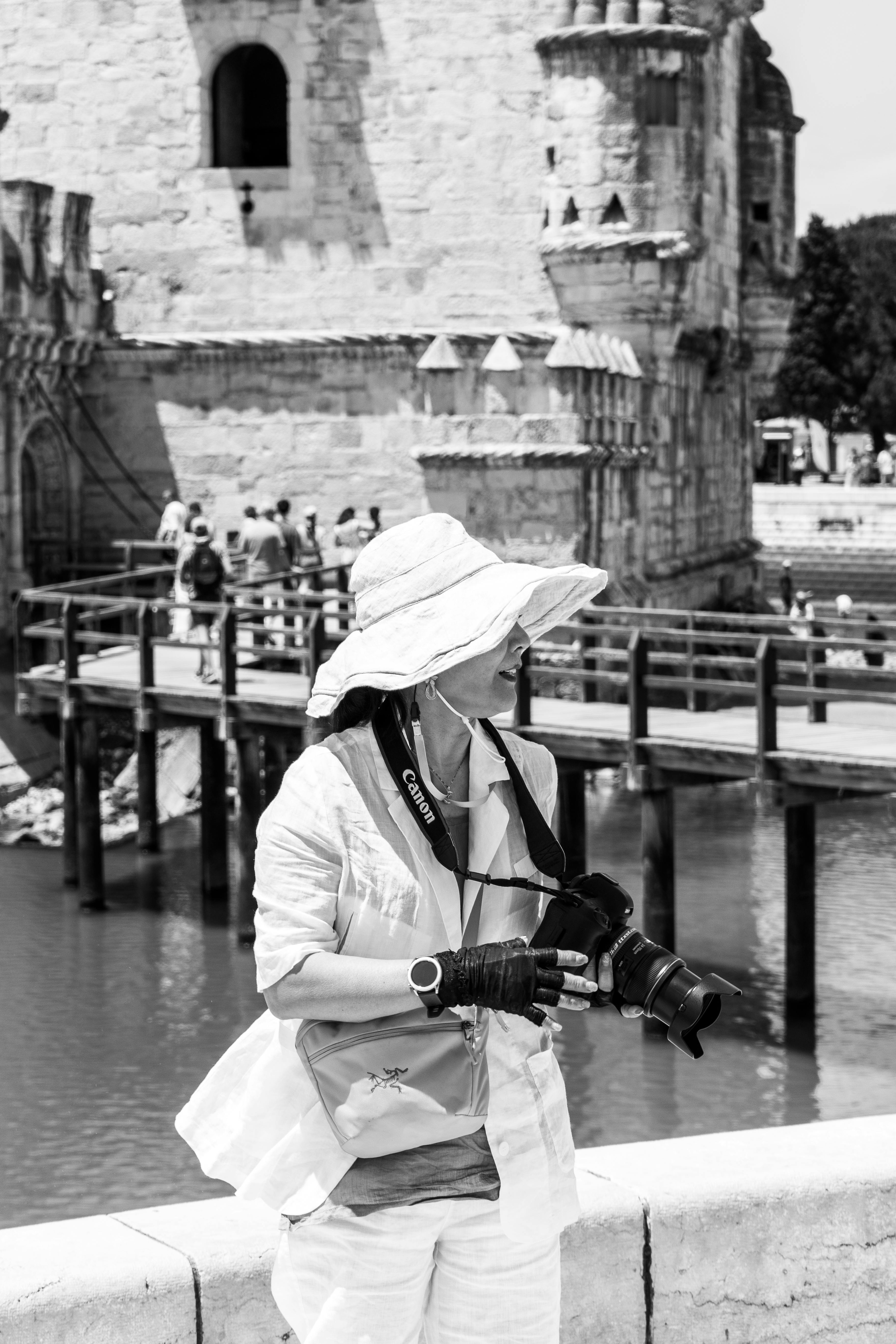 Black and white photo of a female photographer at Belem Tower in Lisbon, Portugal.
