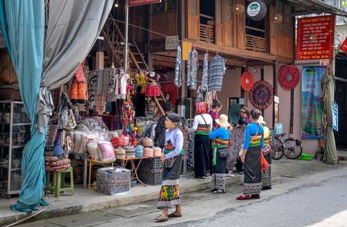 Free Colorful scene at a Vietnamese market with women in traditional clothing exploring textiles and crafts. Stock Photo