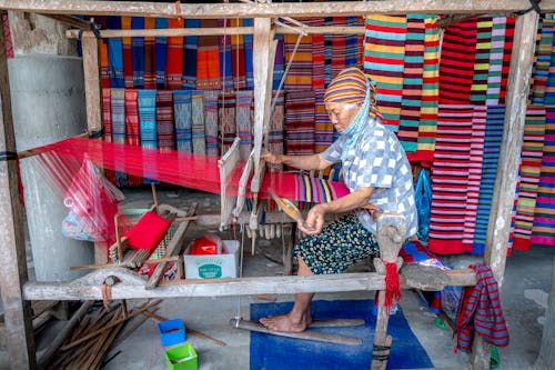 A woman weaving on a loom in a traditional village