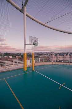 Rooftop basketball court with panoramic city views at sunset, perfect for urban sports enthusiasts.