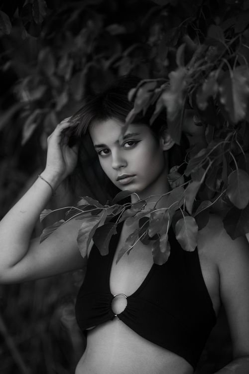 Free Artistic black and white portrait of a woman in a fashion pose with leafy background. Stock Photo