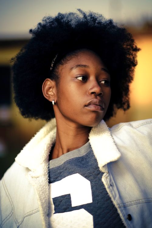 Free Close-up portrait of a young woman with natural hair wearing a white jacket in Orange Farm, South Africa. Stock Photo