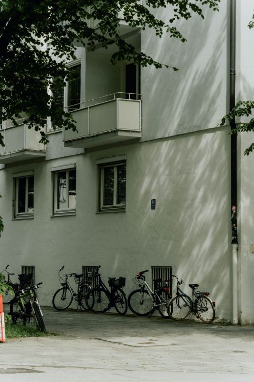 Free Bicycles lined up against a building with balconies in Munich on a sunny day. Stock Photo