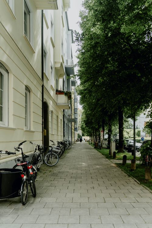 Free Scenic view of bicycles parked along a leafy street in Munich, Germany. Stock Photo