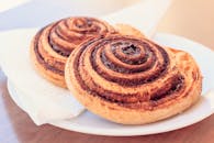 白色盘子上两个新鲜烘烤的肉桂卷的特写镜头