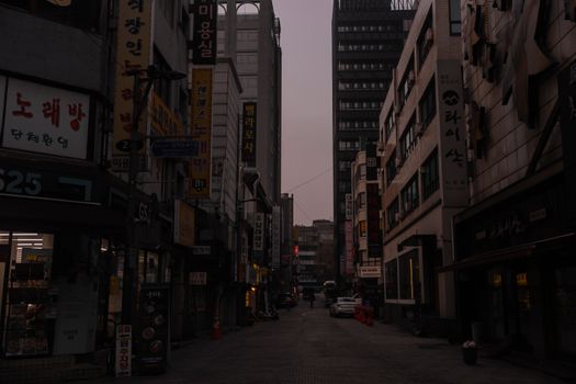 Dimly lit urban alley lined with tall buildings in Seoul, exuding a moody vibe.
