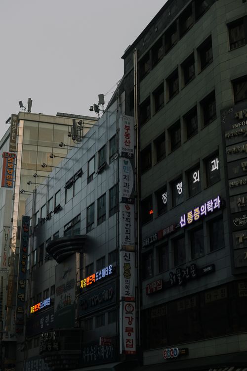 Free Korean street scene featuring city buildings with illuminated signs at twilight, showcasing urban life. Stock Photo