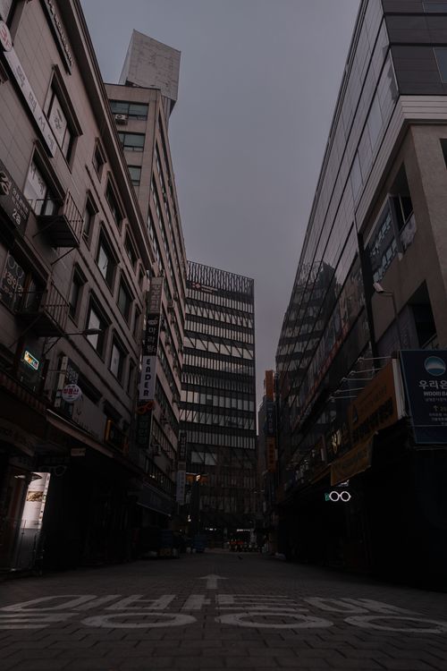 Free Cityscape featuring modern buildings under a cloudy sky, showcasing urban streets and architecture. Stock Photo