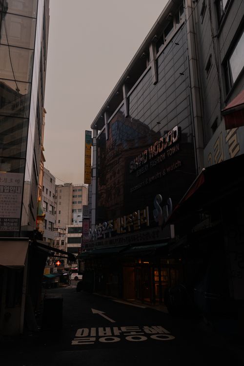 Free A dimly lit urban alleyway featuring towering buildings in a bustling cityscape at dusk. Stock Photo