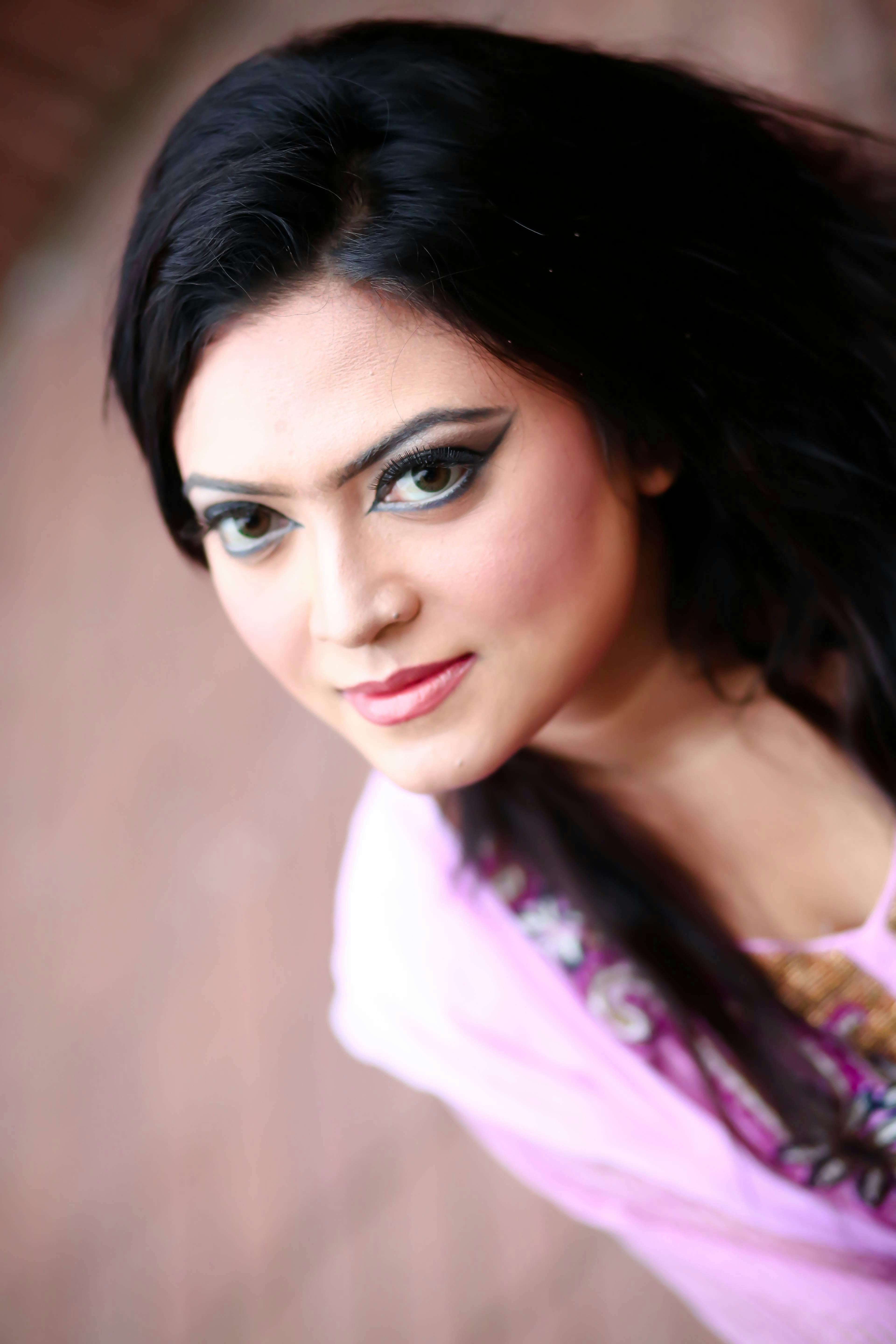 Artistic portrait of a young woman with dramatic eye makeup and long brunette hair.