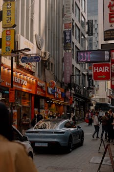Dynamic urban scene with a luxury sports car on a bustling street filled with people and colorful signs.