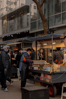 Crowded urban street market with food stalls and people enjoying vibrant city life.