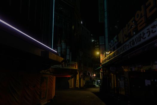 A dimly lit urban alley at night with neon signs and empty streets.