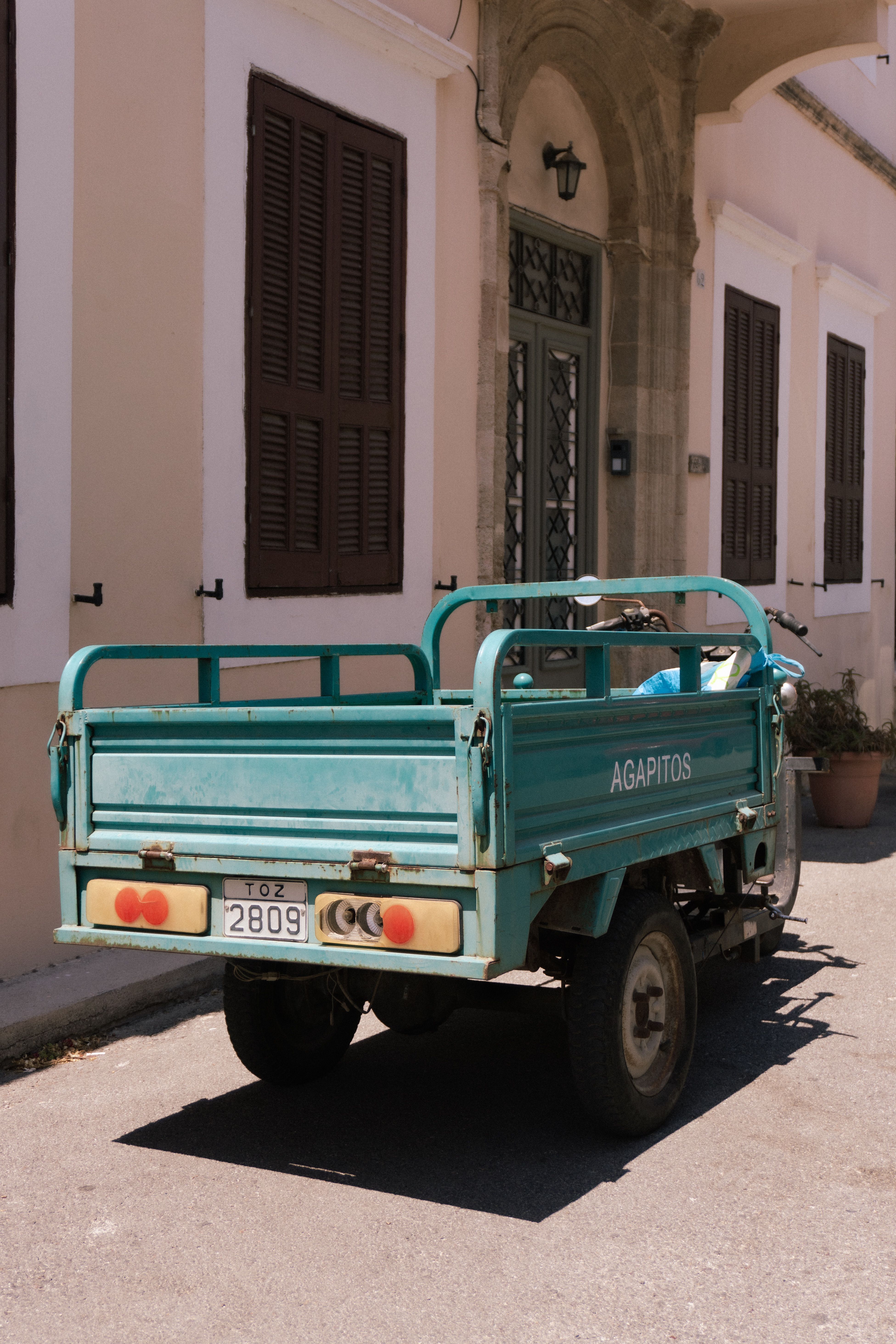 A vintage green truck parked in front of a building on a sunny street, radiating a nostalgic urban vibe.