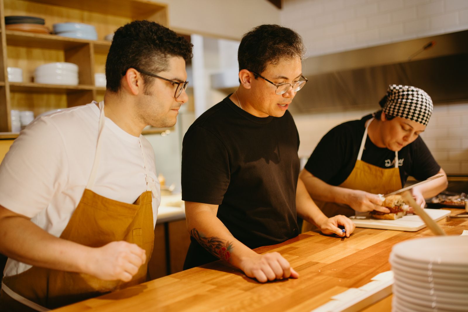 Tres trabajadores de cocina repasando algo junto a la encimera