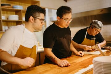 Tres trabajadores de cocina repasando algo junto a la encimera