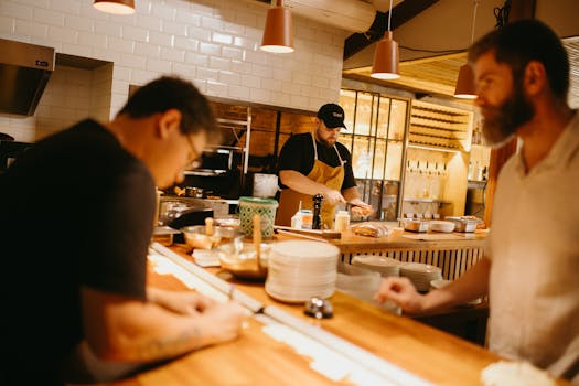 Three chefs working together in a busy restaurant kitchen.