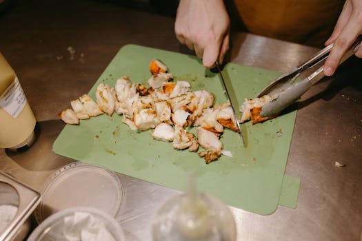 Close-up of hands chopping food on a green cutting board, showcasing culinary preparation.