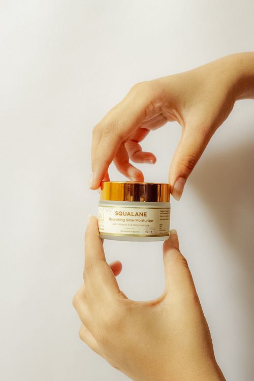 Free Hands holding a cosmetic jar of squalane moisturizer against a white background. Stock Photo