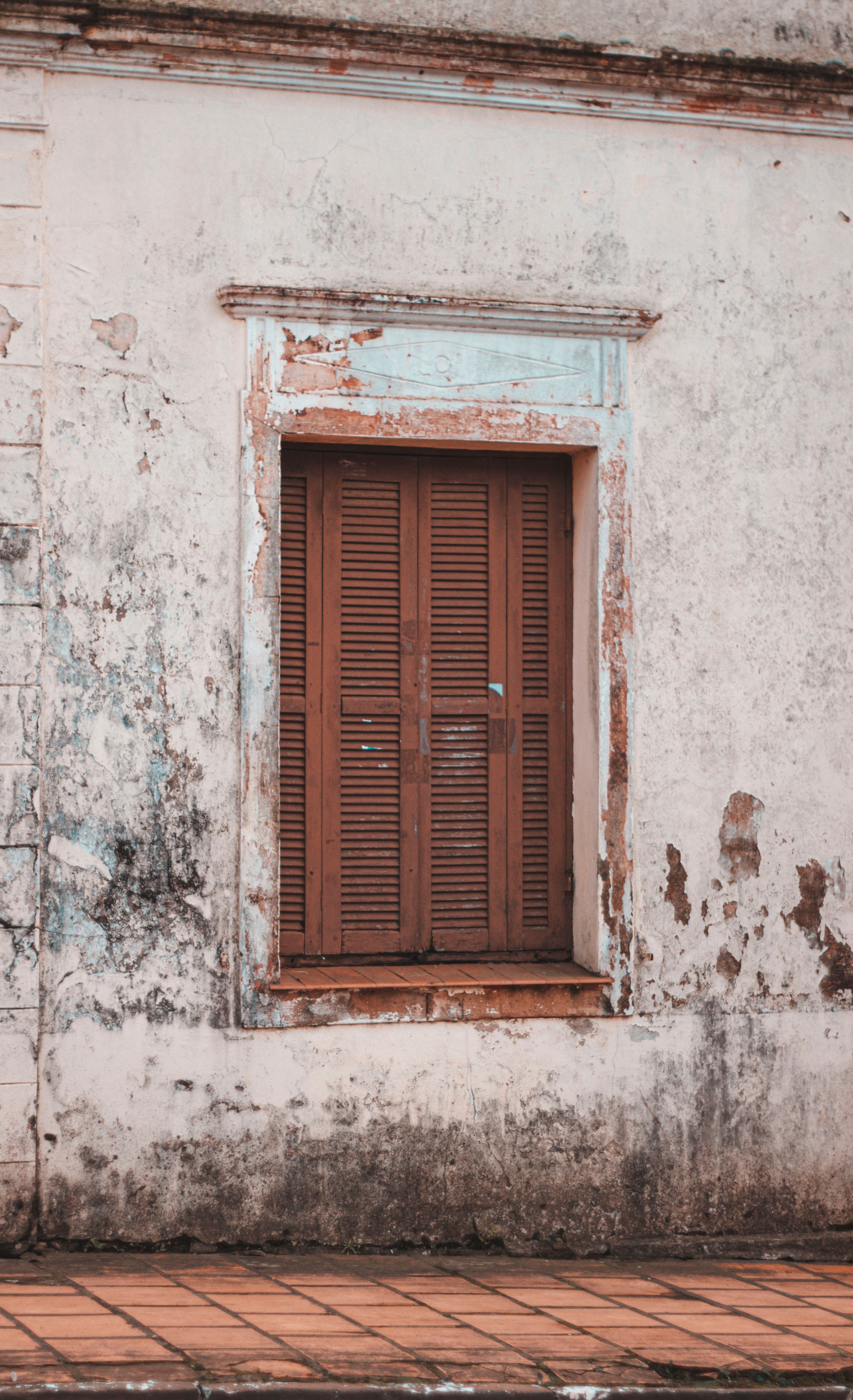 A vintage shuttered window on an old weathered wall in Júlio de Castilhos, Brazil.