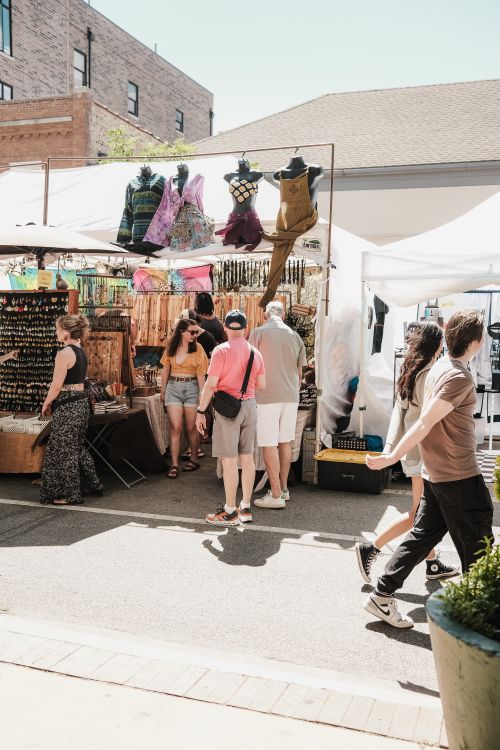 Free Outdoor market in Chicago with people shopping at colorful stalls under sunny skies. Stock Photo