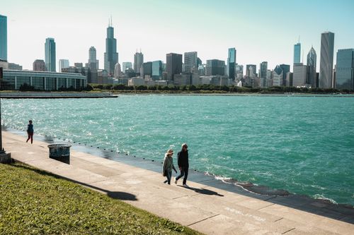 Free Vibrant Chicago skyline overlooking Lake Michigan with people strolling by the promenade. Stock Photo