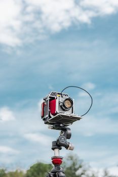 Vintage large format camera on a tripod with a clear blue sky background, capturing a scenic view.