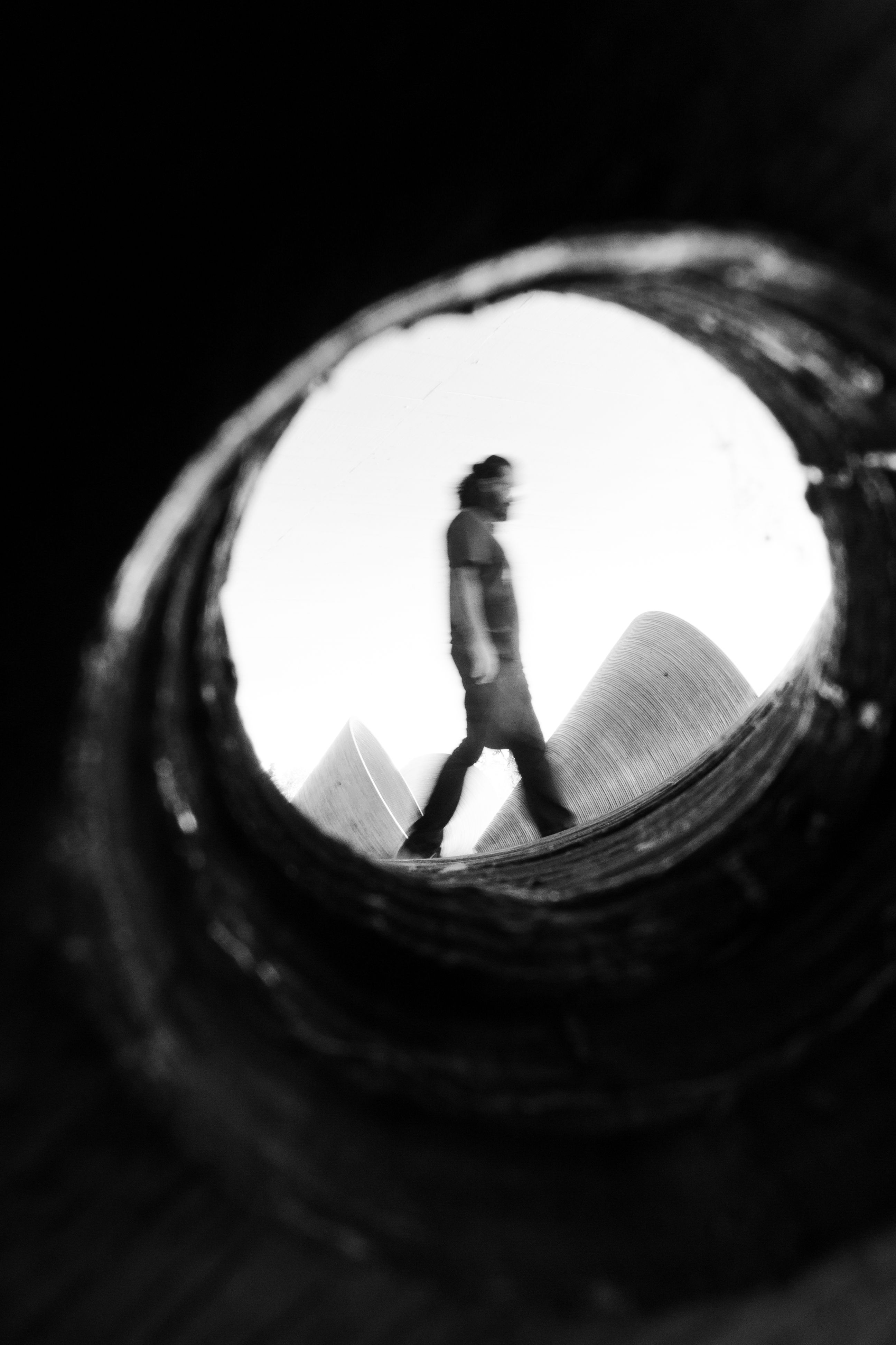 Artistic black and white photo of a man walking inside a circular frame in Curitiba, Brazil.