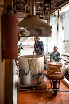 Two people preparing food in a rustic kitchen setting, focusing on traditional cooking methods.