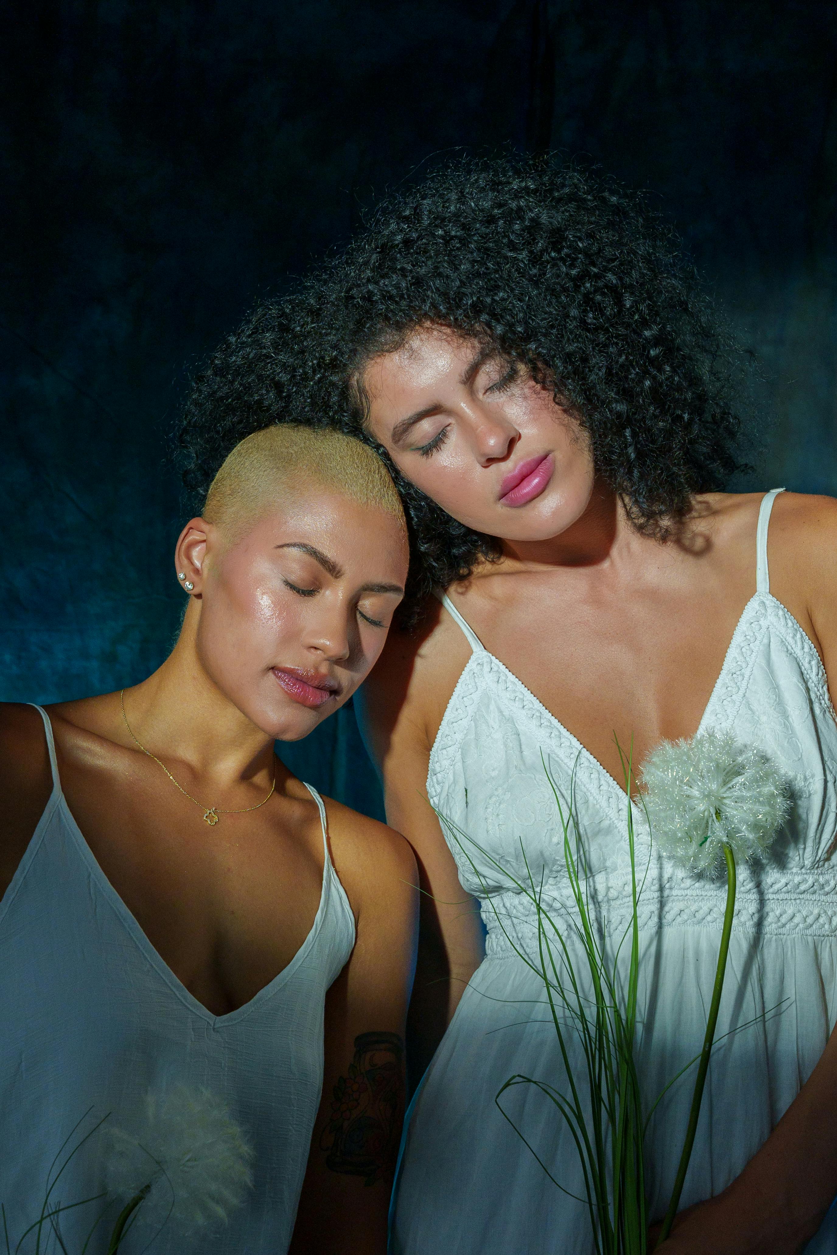 A serene portrait capturing two women in elegant white dresses against a rich background, exuding tranquility.