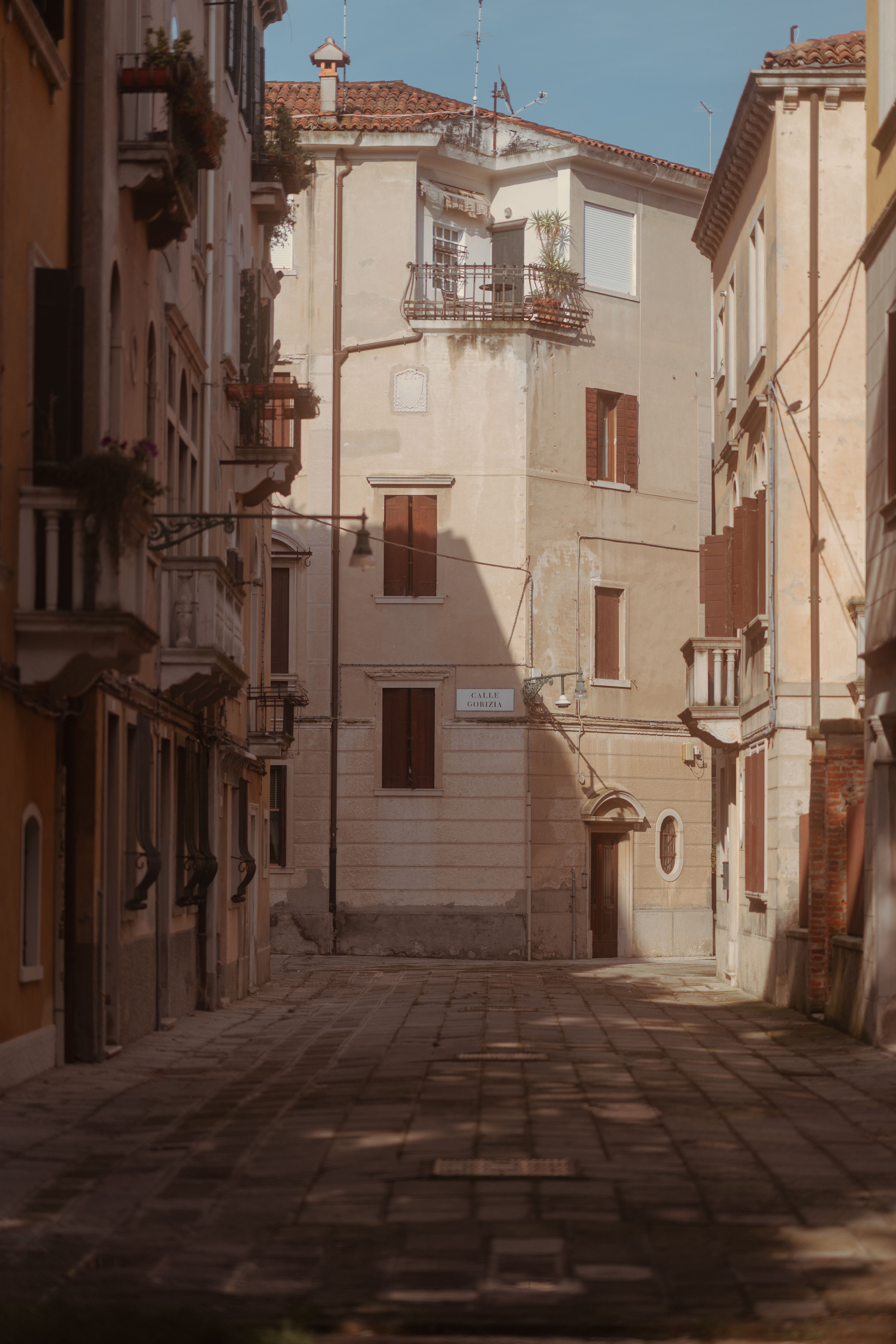 Explore the timeless charm of a Venetian alleyway with classic architecture and sunlit facades. Perfect for travel inspiration.