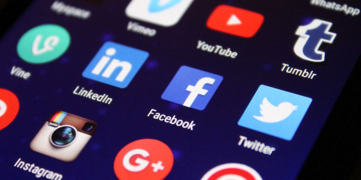 Smartphone displaying social media apps with colorful notification icons on wooden surface showing social media engagement