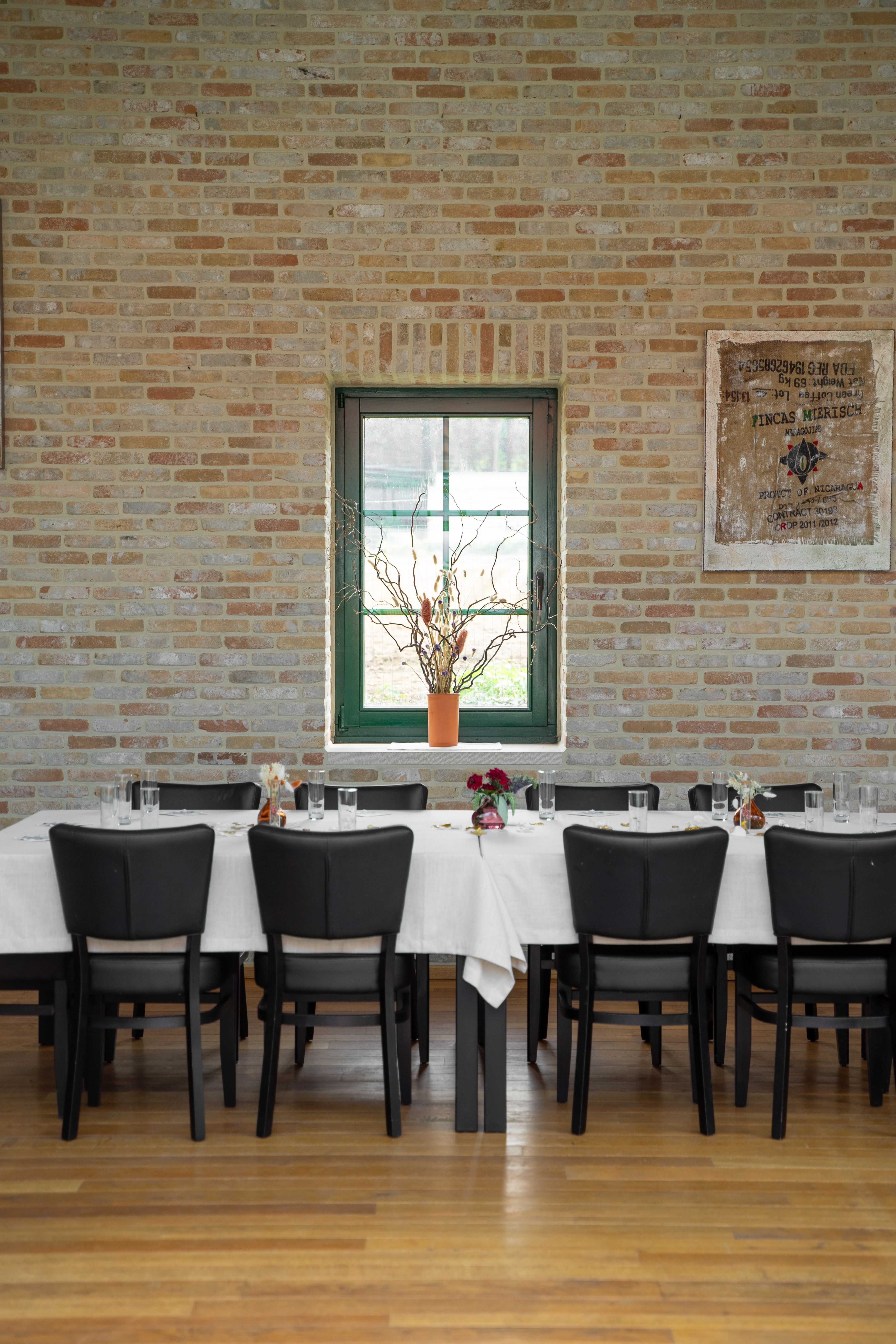 Sophisticated dining area with a white tablecloth table against a brick wall, featuring decor and tableware.