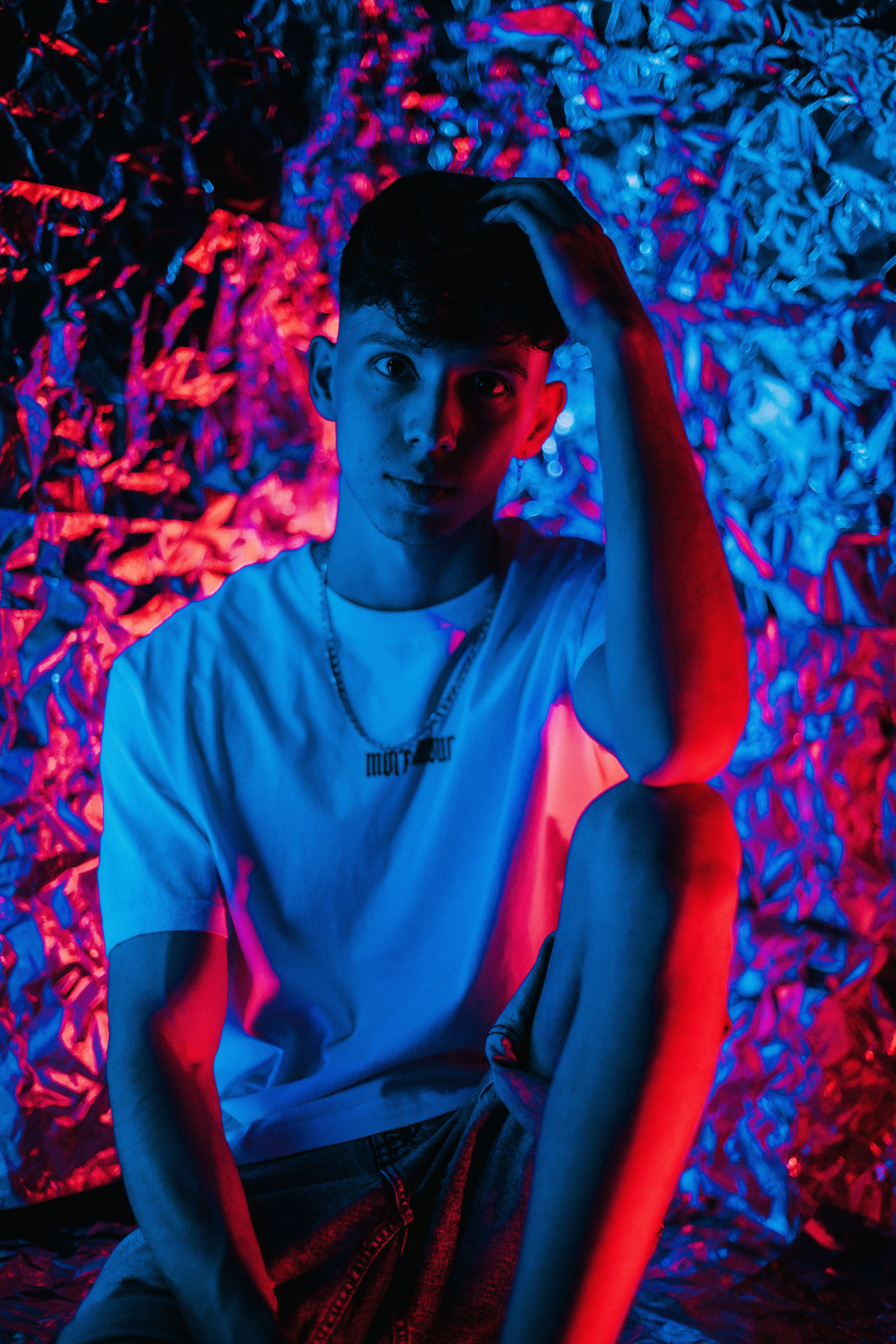 Portrait of a young man in bright neon lighting, creating a modern and edgy look.