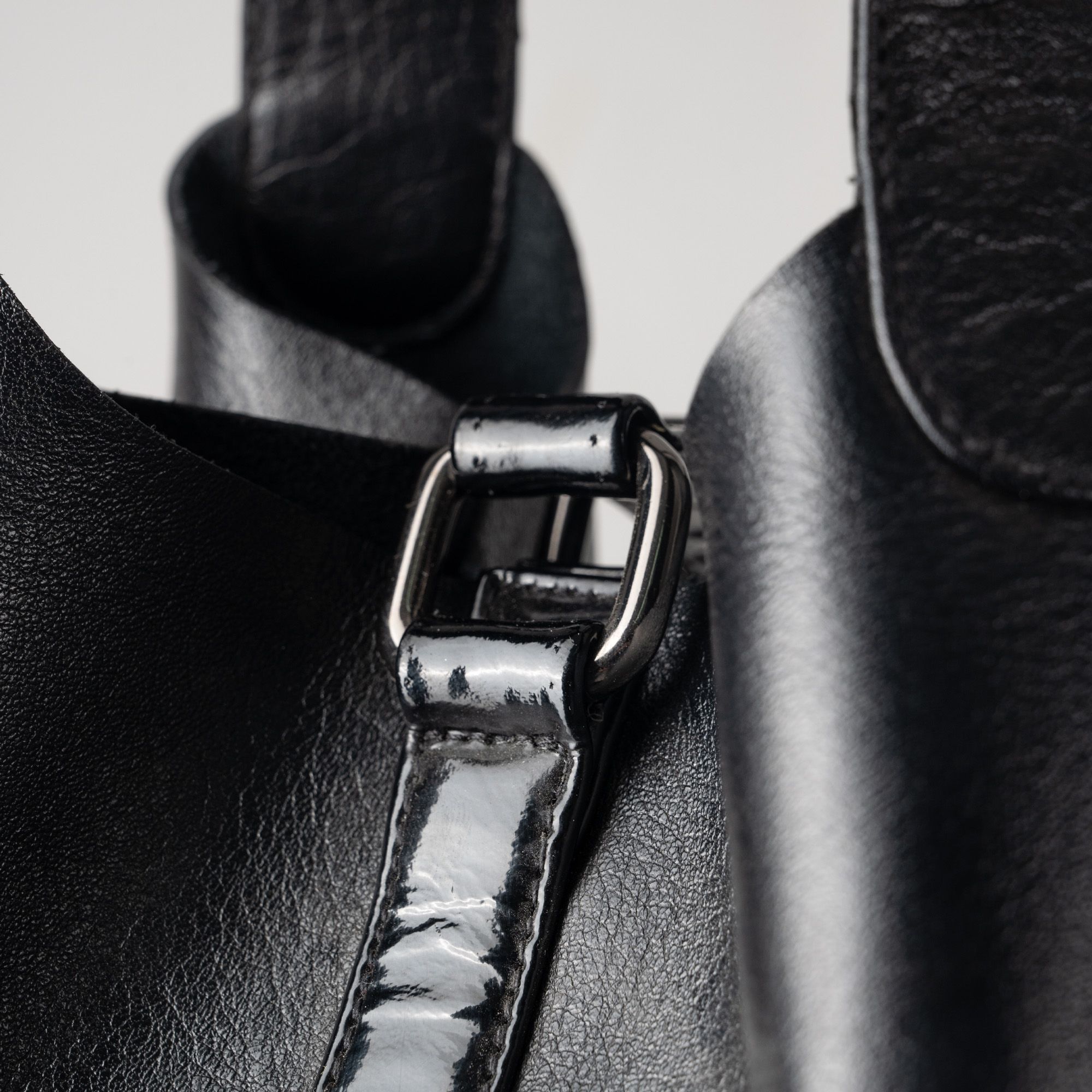Detailed view of a black leather bag showing strap and buckle design.