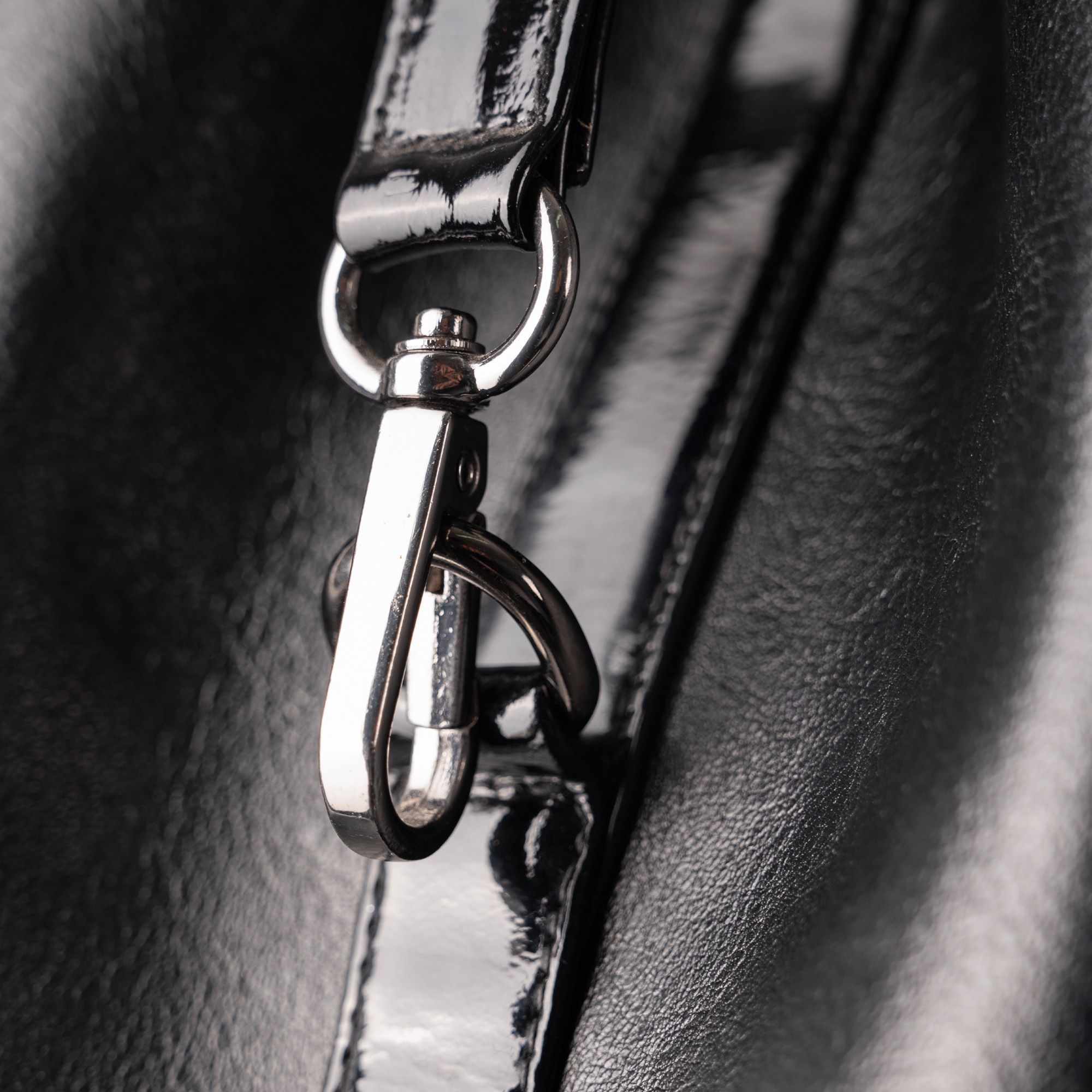 Detailed close-up of a shiny leather bag featuring a metal clasp and strap.