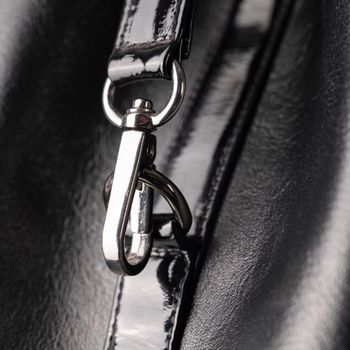 Detailed close-up of a shiny leather bag featuring a metal clasp and strap.
