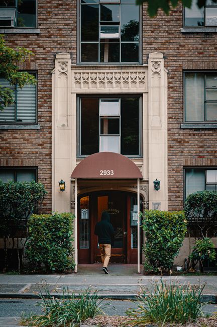 Man entering a residential building in Seattle, WA with greenery.