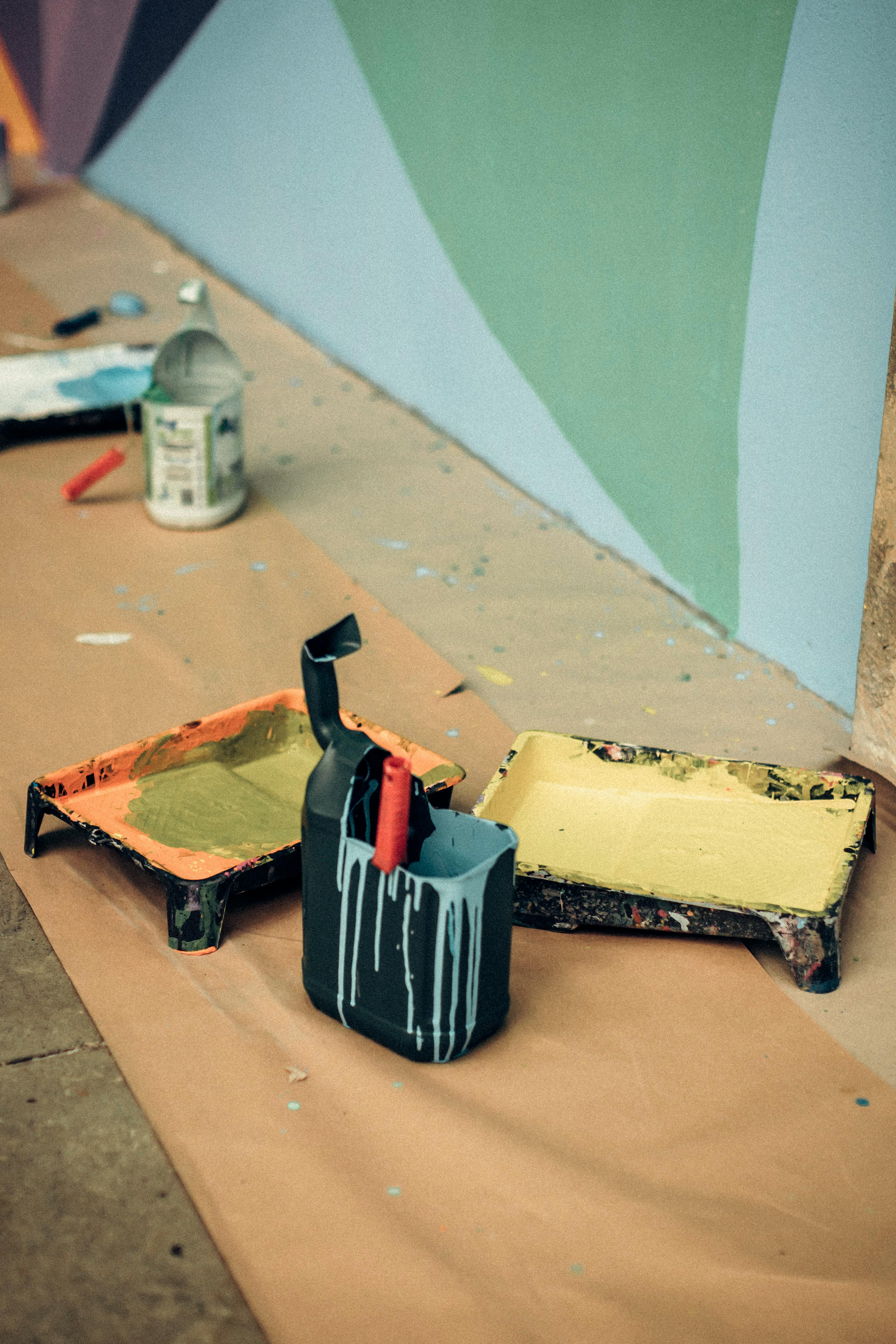 A painting is on the floor with paint brushes and paint