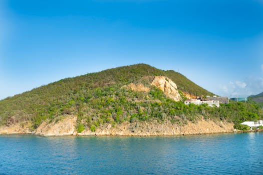 A picturesque green island surrounded by clear blue water and a bright sky.